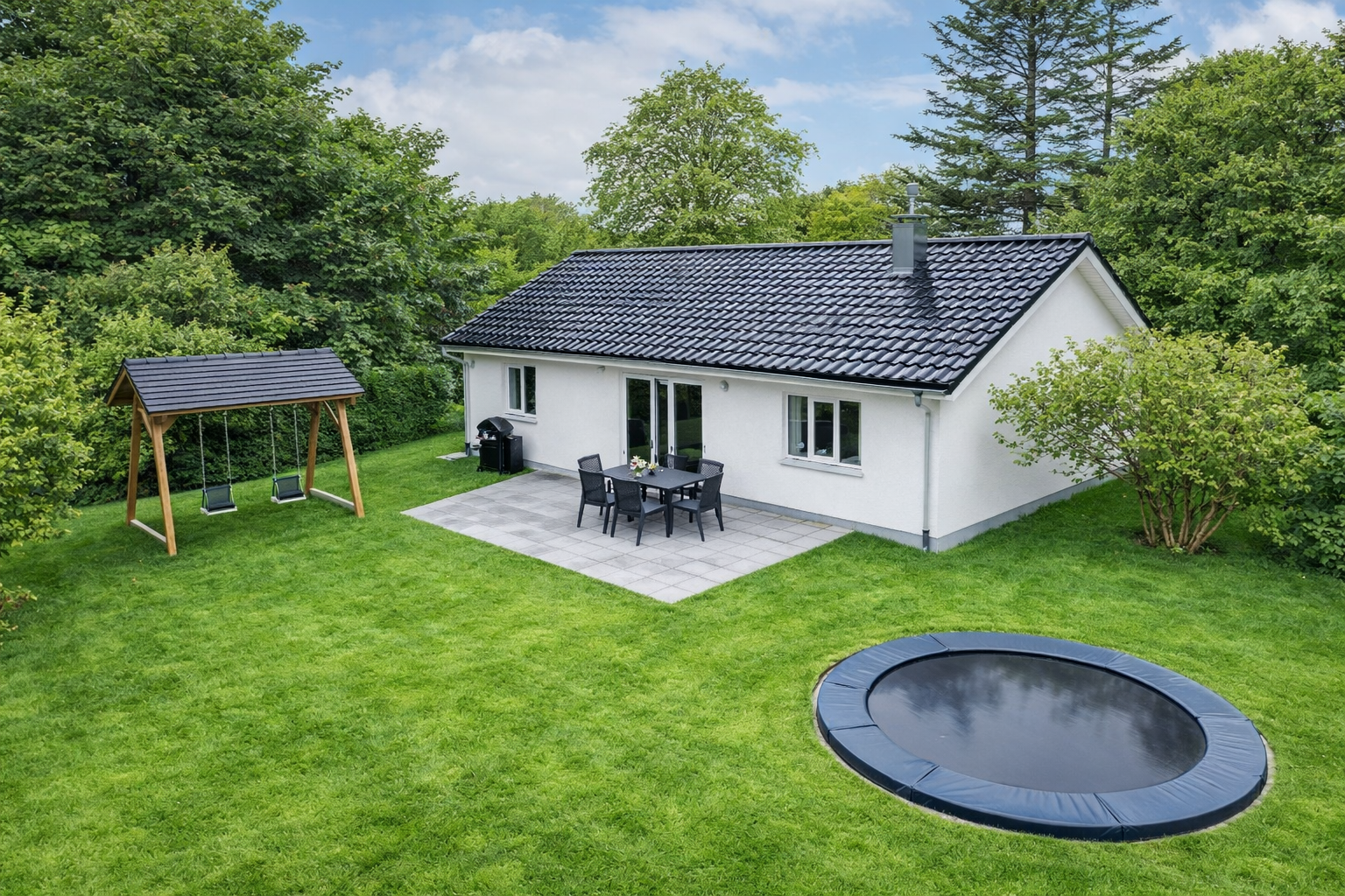 Boligen på Stubdrupvej 2 set udefra, med stor græsplæne, terrasse og legeredskaber